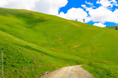 Beautiful mountain panorama with lush greens, blue skies, and puffy clouds