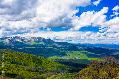 Beautiful mountain panorama with lush greens, blue skies, and puffy clouds © Jim