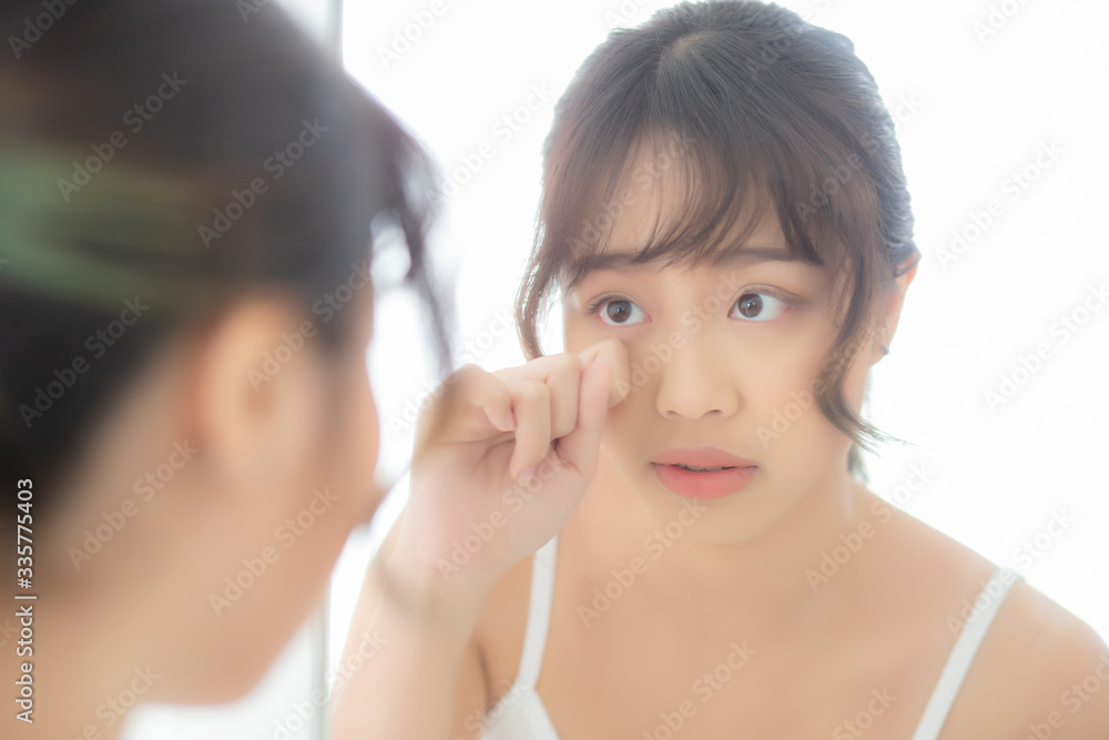 Beautiful and makeup young asian woman looking mirror aging on face and touch eye, beauty asia girl of skincare cosmetic for anti acne wrinkle, healthy care and wellness concept. Beautiful and makeup young asian woman looking mirror aging on face and touch eye, beauty asia girl of skincare cosmetic for anti acne wrinkle, healthy care and wellness concept.