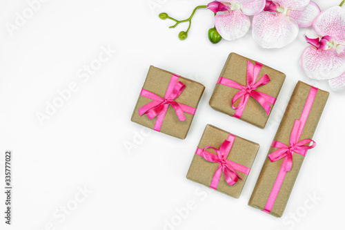 banner of Gift present box with pink ribbon with orchid flowers on white background flat lay. spring concept. Copy space © olga_demina