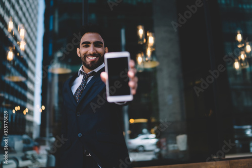 Cheerful businessman showing cellphone on street © BullRun