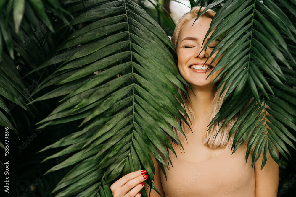 Woman in swimsuit on tropical plants background - obrazy, fototapety, plakaty 
