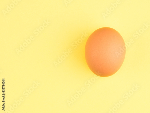 One brown chicken egg on a yellow background. Healthy eating concept