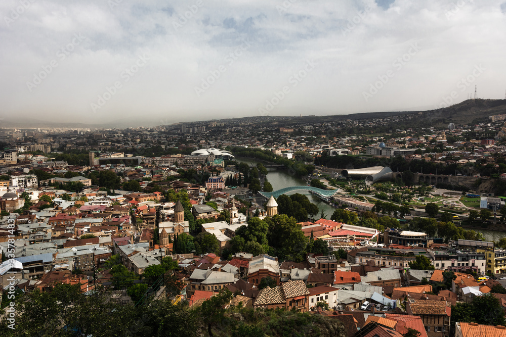 Beautiful landscape view of Old Town Tbilisi with Bridge of Peace and Holy Trinitity Cathedral in cloudy day, Georgia.