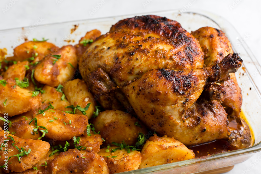 Baked whole chicken with potatoes and herbs in a rustic style. Top view, side view on a light background. Close-up and medium plan. Space for text. Baked whole chicken with potatoes and herbs in a rustic style. Top view, side view on a light background. Close-up and medium plan. Space for text.
