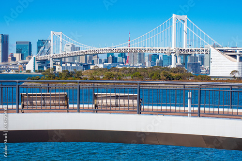 Japan. Tokyo Bridges. Benches overlooking the rainbow bridge. White suspension bridge in Tokyo. The road to the island of Odaiba. Travel to the artificial Islands of the capital of Japan.