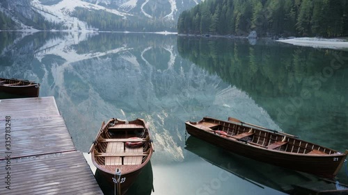 Beautiful landscape of Braies Lake, scenic wooden boats on the water, Alps Mountains Dolomites in Italy.