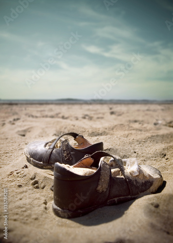Fotografija A lonely forgotten pair of childs shoes discarded in a beach or desert landscape