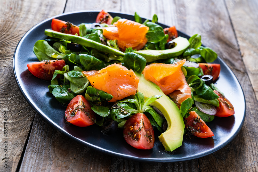 Salmon salad - smoked salmon and vegetables on wooden background
