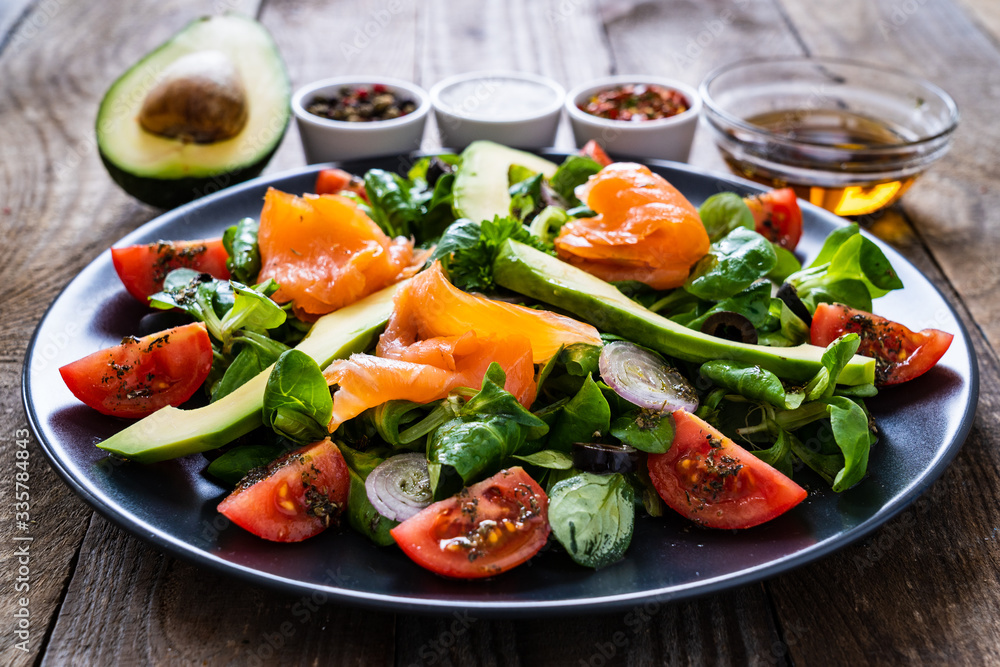 Salmon salad - smoked salmon and vegetables on wooden background
