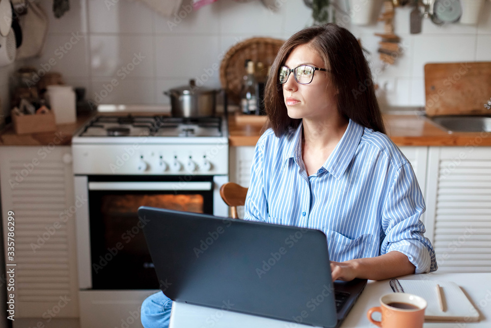 Remote work from home office. Young woman using laptop. Freelancer workplace at kitchen table. Distance education, self isolation, female business, shopping online. Lifestyle moment. Remote work from home office. Young woman using laptop. Freelancer workplace at kitchen table. Distance education, self isolation, female business, shopping online. Lifestyle moment.