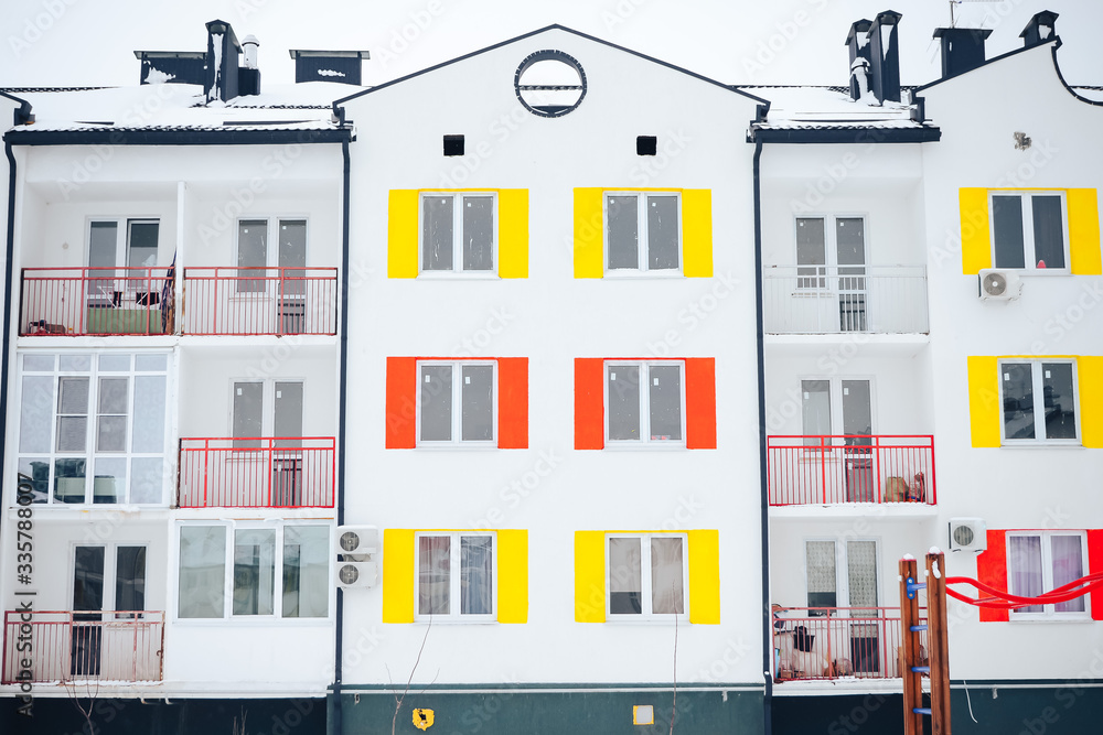 facade of a residential building with windows with multi-colored shutters, front view