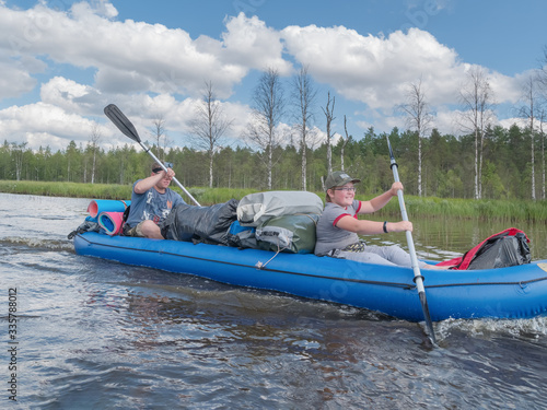 Karelia, Vodlozero - 29.07.2019: Tourists, father and son in boat. Ecotourism, visiting fragile, undisturbed natural areas. Active family holidays. Water rafting in North lakes photo