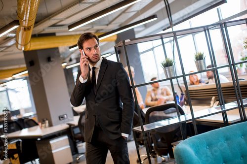 Young businessman wearing black suit using modern smartphone in the office © BGStock72