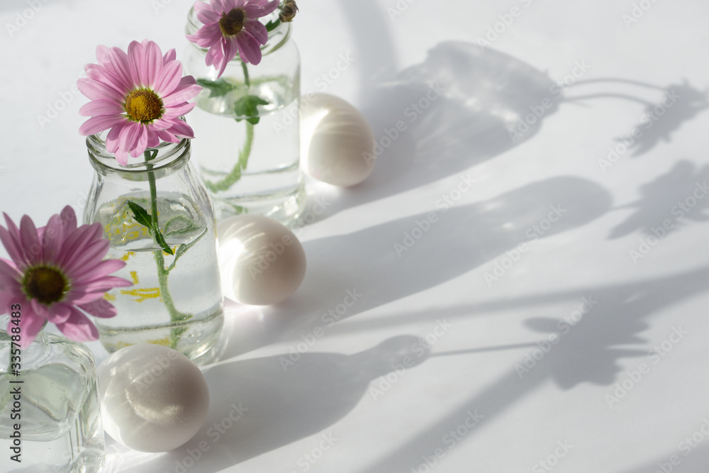 Fototapeta premium Still life with eggs and delicate flowers on a sunny window