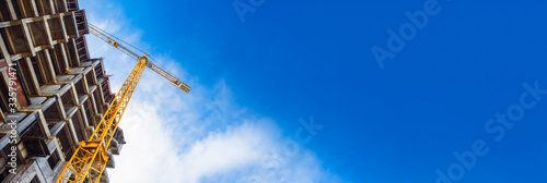 Fotobehang construction site and yellow crane on the background blue sky, panoramic mock-up