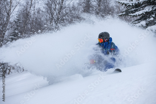 A skier making a powder turn in deep snow on a forest meadow on a snovy morning
