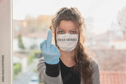 Fotografie young woman wearing surgical mask and gloves is making obscene gesture
