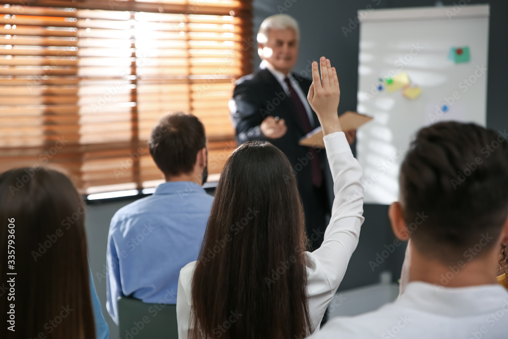 Woman raising hand to ask questions at seminar in office Woman raising hand to ask questions at seminar in office
