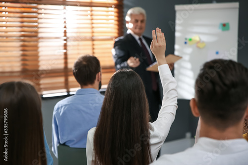 Woman raising hand to ask questions at seminar in office
