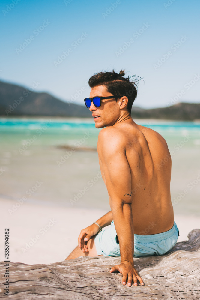 Male model wearing sunglasses and fitness body on the beach posing Male model wearing sunglasses and fitness body on the beach posing
