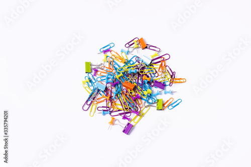 imagen cenital Puñado de clips, chinchetas y pinzas de colores surtidos para organizar documentación sobre fondo blanco