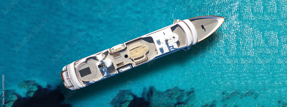 Aerial drone top down ultra wide photo of luxury yacht anchored in tropical exotic island turquoise sea Aerial drone top down ultra wide photo of luxury yacht anchored in tropical exotic island turquoise sea