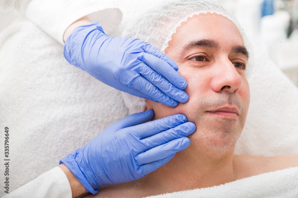 Cosmetology massage of male face with two hands Cosmetology massage of male face with two hands
