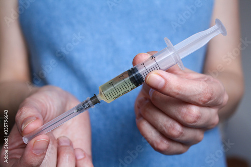 A young, pregnant woman holds a syringe in front of her