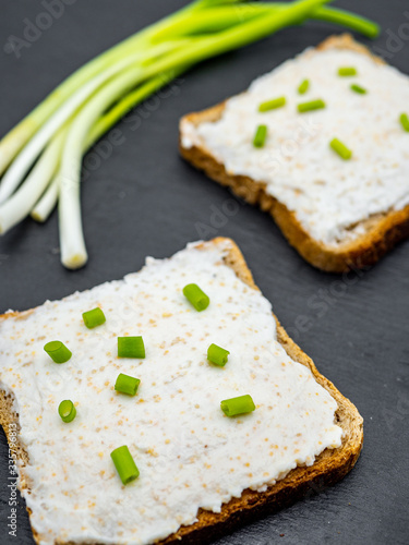 fish roe paste spread on bread slices and green onion on slate breakfast snack concept