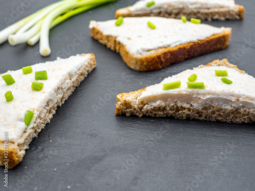fish roe paste spread on bread slices and green onion on slate breakfast snack concept