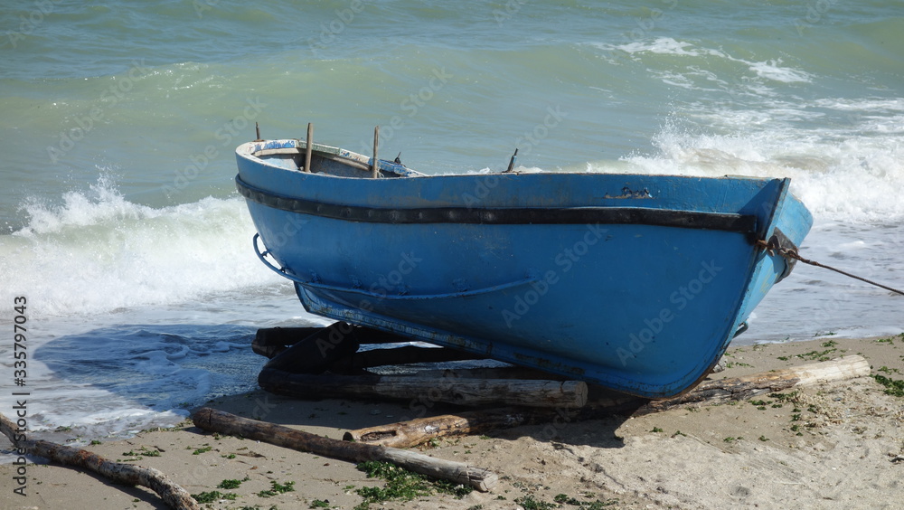 Fishing oars blue boat moored on seashore Fishing oars blue boat moored on seashore