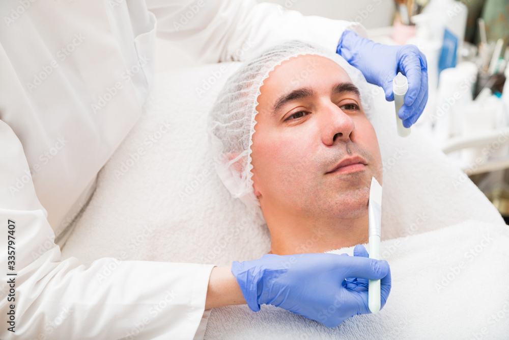 Woman applying with brush mask on man in spa salon Woman applying with brush mask on man in spa salon