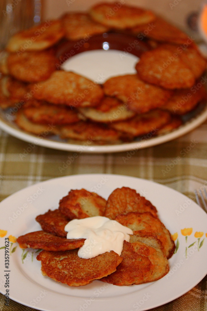 Homemade traditional potato pancakes, served with sour cream, top view.