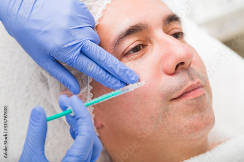 Botox shot from syringe in male face in salon