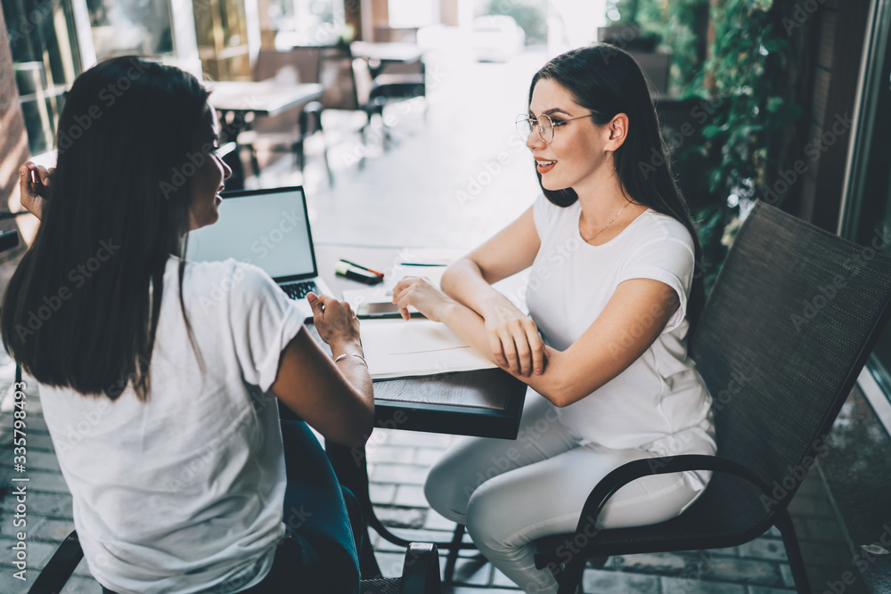 Obraz premium Satisfied young female colleagues discussing business plan in cafe