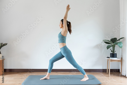 Fototapeta Naklejka Na Ścianę i Meble -  A young Asian woman doing yoga at home