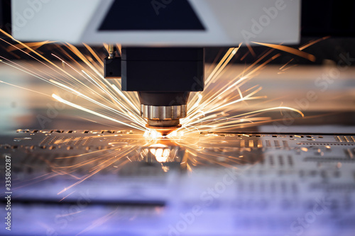 Automated programmed machine. Industrial laser machine cuts out parts in sheet steel. Heat. Sparks during operation of production machine at factory.