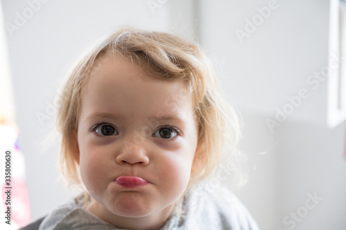 Portrait of a cute blonde girl posing in a kitchen making faces.