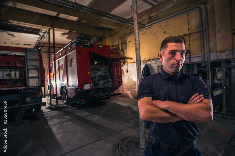 Portrait of confident young fireman standing inside the fire departmant