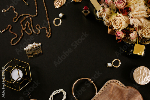 Luxury golden accessories for women's beauty. Dating concept with red lipstick, dry flowers, golden chain, earrings and handbag on black background. Elegant modern template for feminine identity. Flat