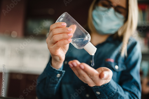 Coronavirus. Sanitizer gel. Cleaning hands antibacterial gel to eliminate germs. Disinfection of hands. Stay at home. Prevent Covid-19 virus. Woman working, wearing protective mask in quarantine.