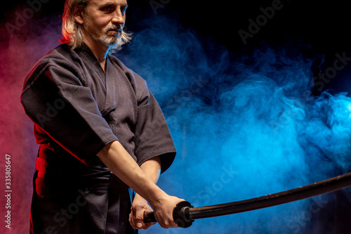 caucasian male kendo fighter in traditional Japanese style of clothing, protective armour, using shinai. practicing fight isolated over smoky room
