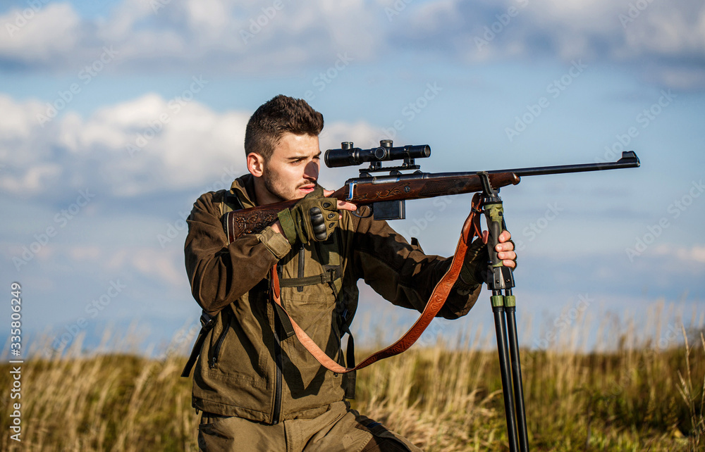 Hunter with hunting gun and hunting form to hunt. Hunter is aiming. Hunter man. Shooter sighting in the target. Hunting period. Male with a gun. Close up. The man is on the hunt. Hunt hunting rifle