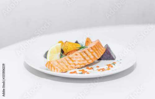 a dish of red fish on a white plate and on white dishes, haute cuisine
