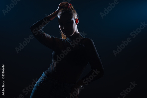 Dark contrast portrait of beautiful young woman with ponytail hairstyle © qunica.com
