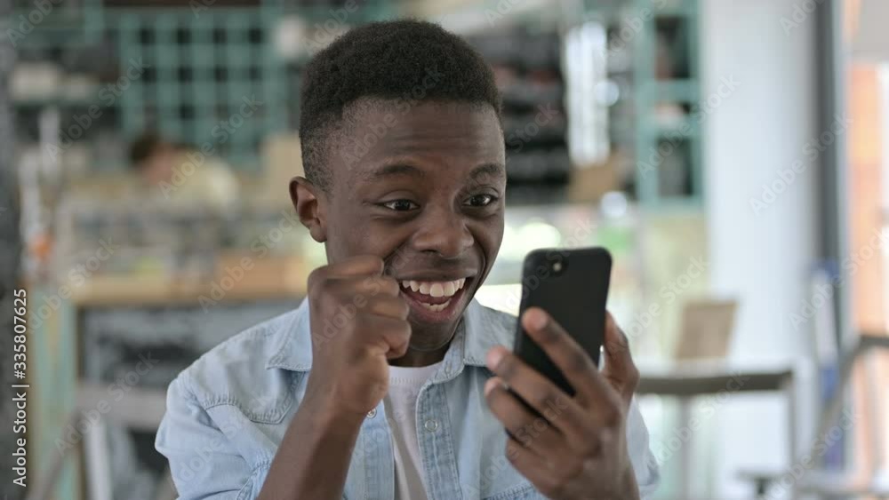 Portrait of Young African Man Celebrating Success on Smartphone Portrait of Young African Man Celebrating Success on Smartphone