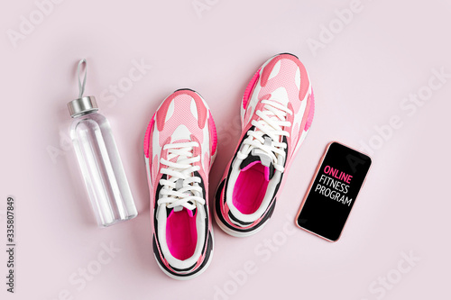 Stay fit. New sneakers and smartphone on a pink background. App for training indoors. Online Fitness program. Home online workout. Top view, flat lay