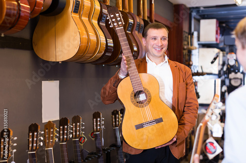Shop assistant offering guitar to teenage