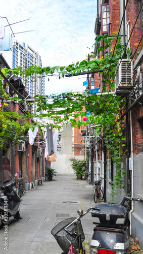 Insight into a residential path in Shanghai, China. The low residential buildings are called Shikumen. Laundry hangs in the alleys, scooters stand and people live here. photo